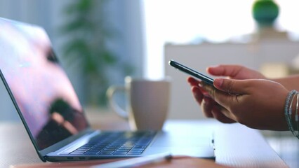 Hands, phone and laptop for remote work and drinking coffee while working on home office table. Freelance woman with smartphone in hand for cloud computing, information technology and internet scroll - Powered by Adobe