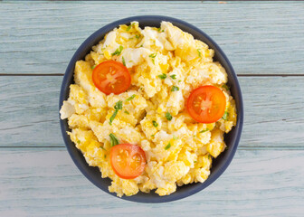 Scrambled eggs on bowl, wooden table, top view
