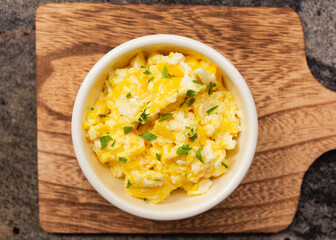 Scrambled eggs on bowl, wooden table, top view