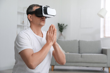 Mature man in VR glasses meditating at home - obrazy, fototapety, plakaty