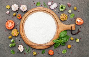 The ingredients for homemade pizza set up on dark stone background.