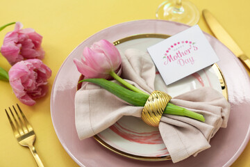 Beautiful table setting with tulip flowers for Mother's Day celebration on yellow background, closeup