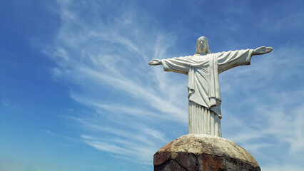 Mini statue of Christ the Redeemer, on top of a rock, with the blue sky.