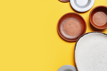 Composition with clean ceramic plates and bowls on yellow background