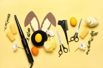 Hairdresser's accessories with Easter eggs, paper bunny ears, flowers and chickens on yellow...