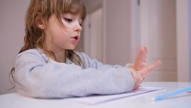 Smart Young Caucasian Girl Preshooler Doing Math Homework Counting Numbers with Her Fingers