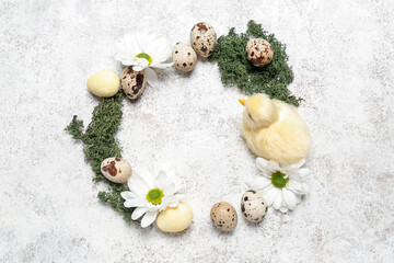 Frame made of Easter quail eggs, baby chicken and chamomile flowers on white grunge background