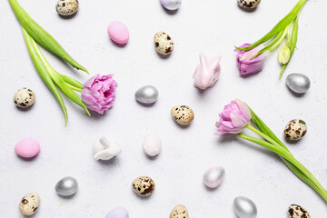 Composition with Easter quail eggs, bunnies and tulip flowers on white background