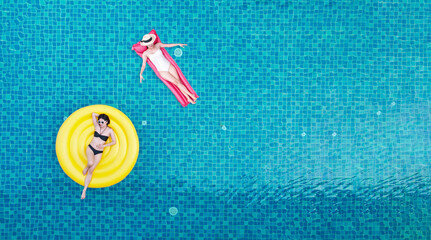 Top view of young asian woman in swimsuit on the pink donut lilo in the swimming pool.