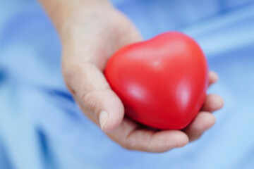 Asian elder senior woman patient holding red heart in hospital.