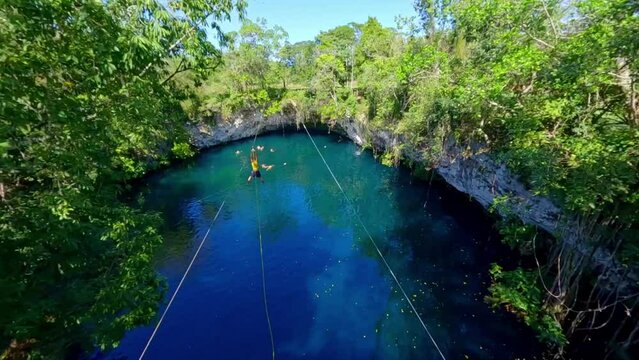 FPV drone view of man ziplining and plunging into blue Dudu lagoon, La Entrada