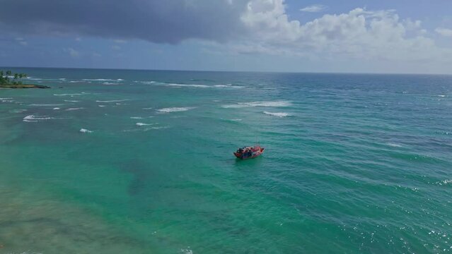 Red fishing boat anchored in turquoise water of Pepillo Salcedo beach, Cabrera