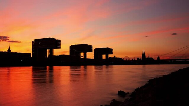 Colorful day to night timelapse of colognes Crane Houses (Kranh&auml;user) and rhine river in the foreground. Smooth camera slide. Beautiful sky with moving clouds. Smooth slide. Sky like fire. Zoom out.