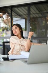 Relaxed millennial Asian businesswoman stretching her arms, taking a break from work