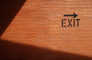 EXIT direction sign on copy space brick shadow wall, concept of finding exit in life trouble or...