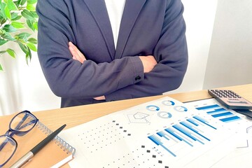 腕を組む　資料を見て悩むビジネスマン