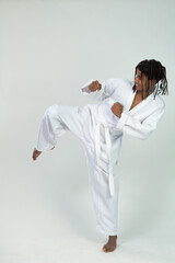 Portrait of a latin teen with braids practicing Taekwondo in studio isolated on white background