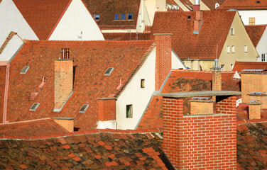 View of urban red tiled roofs with brick chimneys