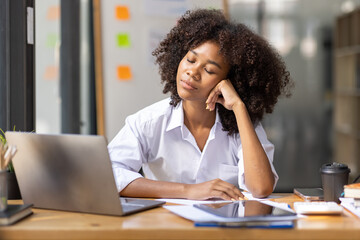 Obraz premium Portrait of tired young business african american woman work with documents tax laptop computer in office. Sad, unhappy, Worried, Depression, or employee life stress concept 