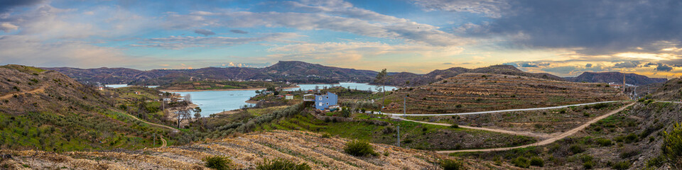 Panoramic view of a mountain lake with clear turquoise-green water against the background of a road...
