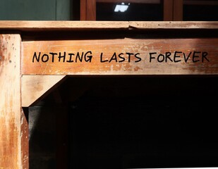Vintage school desk with black copy space shadow and handwritten text NOTHING LASTS FOREVER, means...