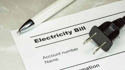 An electric power plug , pen and electricity Bll on the table . electric power consumption