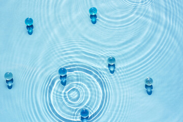 Water blue background with ripples and circles texture and transparent granules