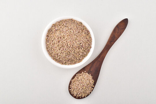 Top view of ajwain seeds in bowl and spoon on white background