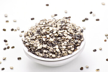 Black split gram in bowl on white background, uncooked urad chilka dal