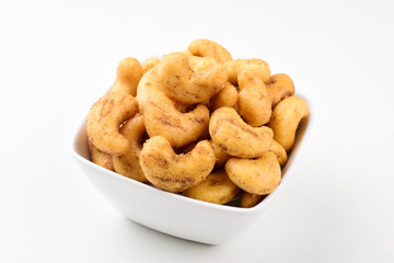Closeup of roasted cashew in bowl on white background