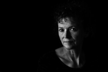 Black and white textured portrait of a middle aged woman with a neutral expression.  Low key...