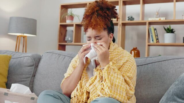 Sick woman, tissue and blowing nose in home for allergies, cold virus and illness bug. Sneeze, flu and allergy of black female on couch in recovery from health problem, medical risk and sinus disease