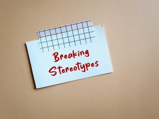 White card stick on office wall background with text message - BREAKING STEREOTYPES to stop...