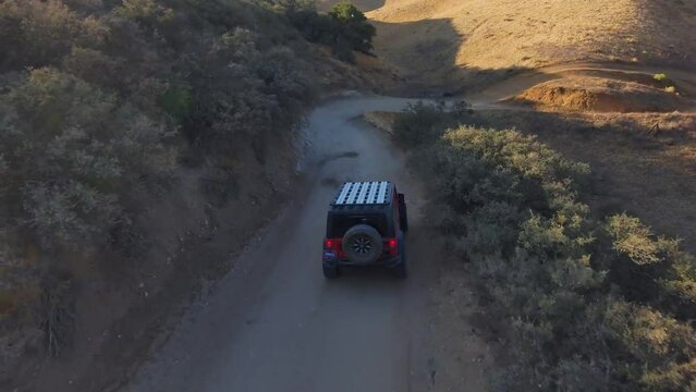 Aerial close tracking shot of red jeep traveling off road