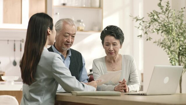 senior asian couple appears unconvinced and confused while listening to a saleswoman