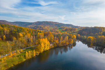 Fojtka water reservoir surrounded by vibrant colored forest at autumn time. Aerial view from drone.