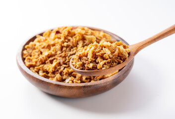 Fried onions and wooden spoon in bowl on white background.