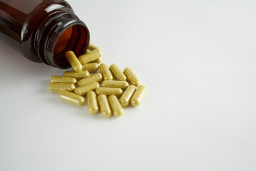 Eye vitamins. Green capsules with a brown bottle on a white background. The concept is prevention and maintenance of eye health.