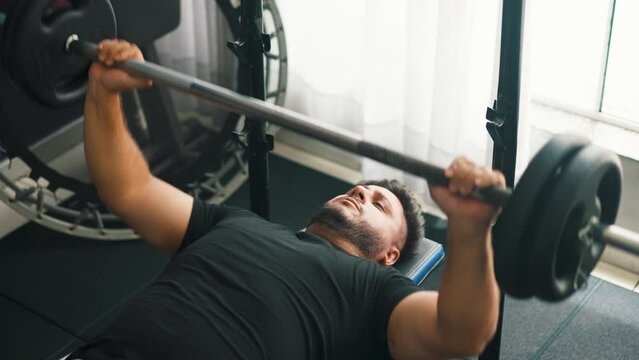 Caucasian young man doing bench press workout with a barbell at the gym