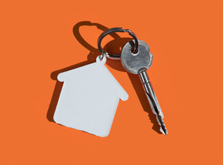 House keys with house shaped keychain on yellow background