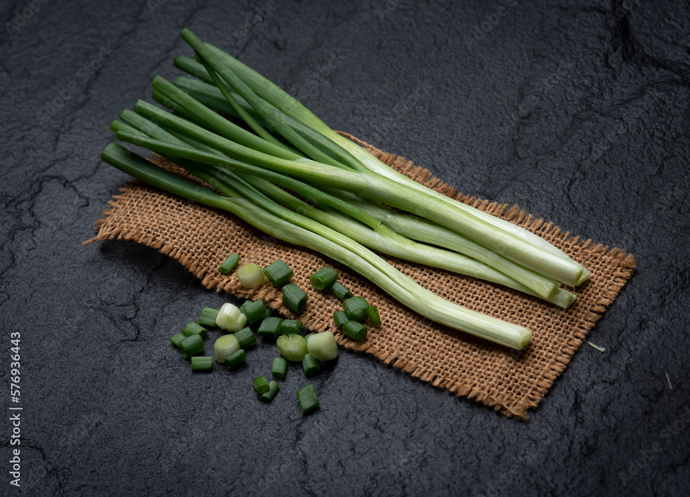 Sticker Sliced green onion on marble board. Black background