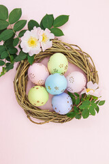 Colored eggs in nest of branches with cherry or apricot branch. Easter. Vertical, horizontal. Copy space