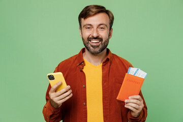 Traveler elderly man 40s years old wear casual clothes hold passport ticket mobile cell phone isolated on plain green background. Tourist travel abroad in free time rest getaway. Air flight concept.