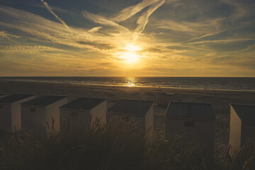 sunset on the beach over beach cabins (The text in the photo: for rent per day, week per month)