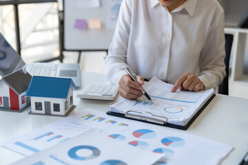 Asian businesswoman thinking and examining financial business principles pointing to statistic data figures chart chart growth in village project accounting statistics concept at the office