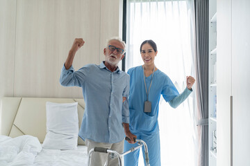 Obraz premium Asian young nurse helping old elderly disable man walking in bedroom.