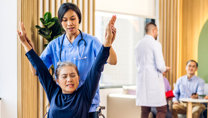 Portrait of asian woman physiotherapist carer helping physical and discussing consulting talk with senior woman patient by doing exercises sitting in wheelchair in rehabilitation at hospital