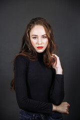 A model in dark clothes with bright make-up on a dark background