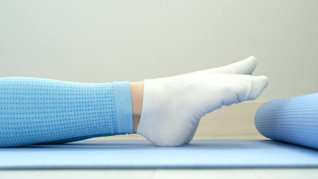 Female legs in socks bend and unbend feet, home workout concert.
