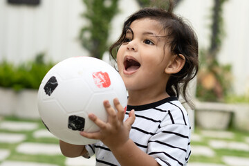 Cute little boy playing soccer with ball outdoors on soccer field